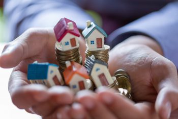 House model and coin money on hand for finance and banking concept. House model and coin money on hand for finance and banking concept.