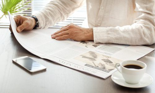 Man reading newspaper on table