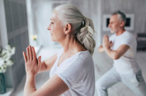 Senior couple at home Senior couple is doing fitness training at home. Doing yoga together. Healthy lifestyle concept.