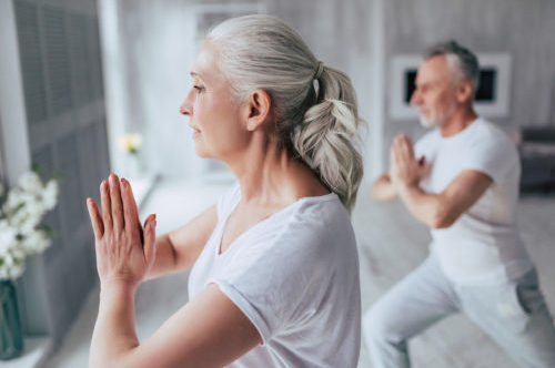 Senior couple at home Senior couple is doing fitness training at home. Doing yoga together. Healthy lifestyle concept.